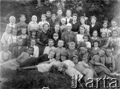 29.06.1945, kołchoz im. Klary Zetkin, Bolszaja Konstantynowka, Koszkinskij rej., Kujbyszewska obł., ZSRR.
Grupa wiejskich dzieci oraz przedstawiciele miejscowych władz (gdy przyjechał fotograf tylko te osoby nie pracowały i mogły pozować do zdjęcia), w pierwszym rzędzie leżą od lewej: Stefania Polak, Żamojdzin (polska Białorusinka), Maria Borkowska, Galina Smirnowa (Rosjanka), Rena Weidenfeld (polska żydówka), Irena Sienkiewicz (obecnie Mrówczyńska), trzej chłopcy siedzący za dziewczynkami to także Polacy, siedzące osoby dorosłe: pierwsza z lewej Antonina Mynowa, z prawej dyrektorka wiejskiej szkoły, to jej donosy przyczyniły się do aresztowania Stanisława Borkowskiego, ojca Marii Borkowskiej.
Fot. NN, zbiory Ośrodka KARTA, udostępniła Maria Borkowska-Flisek.


