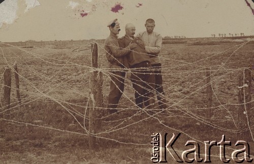1914-1918, brak miejsca.
Trzej żołnierze armii carskiej za zasiekami z drutu kolczastego.
Fot. NN, zbiory Ośrodka KARTA, kolekcję Dominika Piotrowskiego udostępnił Jan Rutkiewicz
 
