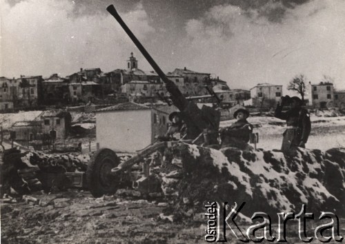Po grudniu 1943, Włochy.
Działania 2 Korpusu Polskiego.  Żołnierze przy dziale oraz żołnierz obserwujący teren przez lornetkę. W oddali widoczna jest panorama włoskiego miasteczka. 
Fot. NN, zbiory Ośrodka KARTA, udostępnili Katarzyna i Tomasz Krzywiccy