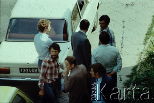 29.05.1979, Warszawa, Polska.
Funkcjonariusze Służby Bezpieczeństwa wynoszą sprzęt fotograficzny i publikacje niezależne, zarekwirowane podczas rewizji w mieszkaniu Marcina Jabłońskiego (drugi od lewej, w kraciastej koszuli), współpracującego z opozycją fotografa, kolportera prasy i wydawnictw niezależnych. Fotografia została wykonana z ukrycia, z dachu sąsiednego budynku na ulicy Pogonowskiego na warszawskim Żoliborzu.
Fot. Witold Olszewski, zbiory Ośrodka KARTA (kolekcję przekazali Nina i Eugeniusz Smolarowie z wydawnictwa Aneks)

