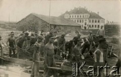 Lata 30., Brześć nad Bugiem, woj. poleskie, Rzeczpospolita Polska.
Prace budowlane w okolicy Szkoły Technicznej. Mężczyźni wywożą ziemię taczkami. W głębi kadru widoczny zaprojektowany przez Jerzego Beila gmach Średniej Szkoły Technicznej im. Marszałka Józefa Piłsudskiego przy ul. 3 Maja (obecnie ul. Puszkińskiej). Szkoła powstała w 1923 roku z inicjatywy inżyniera Oktawiusza Nelarda jako Szkoła Średnia Techniczna Kolejowa.
Fot. NN, kolekcja Eugeniusza Lewickiego, zbiory Ośrodka KARTA
