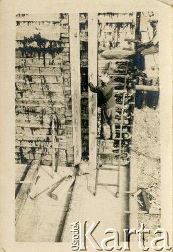 1929-1939, okolice Brześcia nad Bugiem, woj. poleskie, Rzeczpospolita Polska.
Robotnicy wznoszą drewnianą konstrukcję uszczelnioną smołą. Kanał Muchawiecki (Kanał Dniepr-Bug, zwany również Kanałem Królewskim lub Kanałem Rzeczypospolitej) otwarty w 1848 roku kanał żeglowny łączący Dniepr z Wisłą poprzez Pinę (dopływ Prypeci) i Muchawiec (prawostronny dopływ Bugu) stanowiący część szlaku wodnego łączącego Morze Bałtyckie z Morzem Czarnym. Pierwszy odcinek Kanału zbudowano w latach 1775-1784, następnie, w latach 1846-1848, Kanał był rozbudowywany przez władze rosyjskie. W latach 1929-1939, w czasach administracji II Rzeczypospolitej, poddawany gruntowym pracom remontowym. 
Fot. NN, kolekcja Eugeniusza Lewickiego, zbiory Ośrodka KARTA