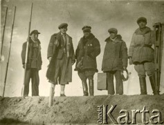 1929-1939, okolice Brześcia nad Bugiem, woj. poleskie, Rzeczpospolita Polska.
Grupa mężczyzn stoi na wale na brzegu rzeki. 2. z lewej Eugeniusz Lewicki. Obok niego, w kożuchu i czapce z orzełkiem, nadzorujący roboty urzędnik państwowy. 
Kanał Muchawiecki (Kanał Dniepr-Bug, zwany również Kanałem Królewskim lub Kanałem Rzeczypospolitej) otwarty w 1848 roku kanał żeglowny łączący Dniepr z Wisłą poprzez Pinę (dopływ Prypeci) i Muchawiec (prawostronny dopływ Bugu) ) stanowiący część szlaku wodnego łączącego Morze Bałtyckie z Morzem Czarnym. Pierwszy odcinek Kanału zbudowano w latach 1775-1784, następnie, w latach 1846-1848, Kanał był rozbudowywany przez władze rosyjskie. W latach 1929-1939, w czasach administracji II Rzeczypospolitej, poddawany gruntowym pracom remontowym. 
Fot. NN, kolekcja Eugeniusza Lewickiego, zbiory Ośrodka KARTA