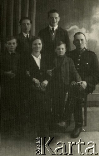 1939-1941, Kozienice, Polska.
Mężczyzna w mundurze oraz kobieta i czterej chłopcy, prawdopodobnie rodzina - mąż z żoną i synami.
Zdjęcie wykonane w atelier fotograficznym żydowskiego fotografa Chaima Bernemana. Przed wojną zakład mieścił się w Kozienicach na rogu ulic Warszawskiej i Maciejowickiej, przed wybuchem wojny albo już w czasie niemieckiej okupacji  został przeniesiony na ulicę Lubelską 13. Cała kolekcja jest datowana na okres od drugiej połowy lat 30-tych do roku 1941, kiedy Chaim Berneman wraz z rodziną został zesłany do obozu pracy w Wolanowie. Berneman zmarł po ucieczce z obozu.
Fot. Chaim Berneman (Chaim Berman), zbiory Ośrodka KARTA