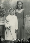 Druga połowa lat 30. do 1939, Kozienice, Polska.
Pamiątka Pierwszej Komunii Świętej - dziewczynka w białej sukience trzyma kwiaty, obok stoi jej siostra.
Zdjęcie wykonane w atelier fotograficznym żydowskiego fotografa Chaima Bernemana. Przed wojną zakład mieścił się w Kozienicach na rogu ulic Warszawskiej i Maciejowickiej, tuż przed wybuchem wojny albo już w czasie niemieckiej okupacji  został przeniesiony na ulicę Lubelską 13. Cała kolekcja jest datowana na okres od drugiej połowy lat 30-tych do roku 1941, kiedy Chaim Berneman wraz z rodziną został zesłany do obozu pracy w Wolanowie. Berneman zmarł po ucieczce z obozu.
Fot. Chaim Berneman (Chaim Berman), zbiory Ośrodka KARTA