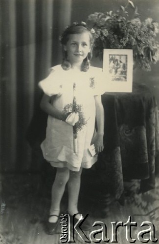Druga połowa lat 30. do 1939, Kozienice, Polska.
Pamiątka Pierwszej Komunii Świętej - portret dziewczynki w białej sukience.
Zdjęcie wykonane w atelier fotograficznym żydowskiego fotografa Chaima Bernemana. Przed wojną zakład mieścił się w Kozienicach na rogu ulic Warszawskiej i Maciejowickiej, tuż przed wybuchem wojny albo już w czasie niemieckiej okupacji  został przeniesiony na ulicę Lubelską 13. Cała kolekcja jest datowana na okres od drugiej połowy lat 30-tych do roku 1941, kiedy Chaim Berneman wraz z rodziną został zesłany do obozu pracy w Wolanowie. Berneman zmarł po ucieczce z obozu.
Fot. Chaim Berneman (Chaim Berman), zbiory Ośrodka KARTA