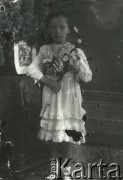 Druga połowa lat 30. do 1939, Kozienice, Polska.
Pamiątka Pierwszej Komunii Świętej - portret dziewczynki w białej sukience.
Zdjęcie wykonane w atelier fotograficznym żydowskiego fotografa Chaima Bernemana. Przed wojną zakład mieścił się w Kozienicach na rogu ulic Warszawskiej i Maciejowickiej, tuż przed wybuchem wojny albo już w czasie niemieckiej okupacji  został przeniesiony na ulicę Lubelską 13. Cała kolekcja jest datowana na okres od drugiej połowy lat 30-tych do roku 1941, kiedy Chaim Berneman wraz z rodziną został zesłany do obozu pracy w Wolanowie. Berneman zmarł po ucieczce z obozu.
Fot. Chaim Berneman (Chaim Berman), zbiory Ośrodka KARTA