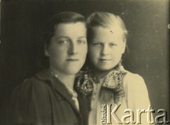 Druga połowa lat 30. do 1941, Kozienice, Polska.
Młoda kobieta z dziewczynką, prawdopodobnie matka z córką.
Zdjęcie wykonane w atelier fotograficznym żydowskiego fotografa Chaima Bernemana. Przed wojną zakład mieścił się w Kozienicach na rogu ulic Warszawskiej i Maciejowickiej, przed wybuchem wojny albo już w czasie niemieckiej okupacji  został przeniesiony na ulicę Lubelską 13. Cała kolekcja jest datowana na okres od drugiej połowy lat 30-tych do roku 1941, kiedy Chaim Berneman wraz z rodziną został zesłany do obozu pracy w Wolanowie. Berneman zmarł po ucieczce z obozu.
Fot. Chaim Berneman (Chaim Berman), zbiory Ośrodka KARTA