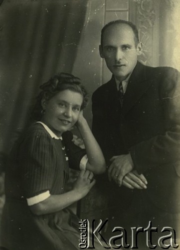 Druga połowa lat 30. do 1941, Kozienice, Polska.
Portret młodej kobiety w ciemnej sukience i mężczyzny w garniturze.
Zdjęcie wykonane w atelier fotograficznym żydowskiego fotografa Chaima Bernemana. Przed wojną zakład mieścił się w Kozienicach na rogu ulic Warszawskiej i Maciejowickiej, przed wybuchem wojny albo już w czasie niemieckiej okupacji  został przeniesiony na ulicę Lubelską 13. Cała kolekcja jest datowana na okres od drugiej połowy lat 30-tych do roku 1941, kiedy Chaim Berneman wraz z rodziną został zesłany do obozu pracy w Wolanowie. Berneman zmarł po ucieczce z obozu.
Fot. Chaim Berneman (Chaim Berman), zbiory Ośrodka KARTA