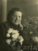 Druga połowa lat 30. do 1941, Kozienice, Polska.
Portret kobiety z bukietem kwiatów.
Zdjęcie wykonane w atelier fotograficznym żydowskiego fotografa Chaima Bernemana. Przed wojną zakład mieścił się w Kozienicach na rogu ulic Warszawskiej i Maciejowickiej, przed wybuchem wojny albo już w czasie niemieckiej okupacji  został przeniesiony na ulicę Lubelską 13. Cała kolekcja jest datowana na okres od drugiej połowy lat 30-tych do roku 1941, kiedy Chaim Berneman wraz z rodziną został zesłany do obozu pracy w Wolanowie. Berneman zmarł po ucieczce z obozu.
Fot. Chaim Berneman (Chaim Berman), zbiory Ośrodka KARTA
