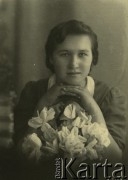Druga połowa lat 30. do 1941, Kozienice, Polska.
Portret dziewczyny z bukietem kwiatów.
Zdjęcie wykonane w atelier fotograficznym żydowskiego fotografa Chaima Bernemana. Przed wojną zakład mieścił się w Kozienicach na rogu ulic Warszawskiej i Maciejowickiej, przed wybuchem wojny albo już w czasie niemieckiej okupacji  został przeniesiony na ulicę Lubelską 13. Cała kolekcja jest datowana na okres od drugiej połowy lat 30-tych do roku 1941, kiedy Chaim Berneman wraz z rodziną został zesłany do obozu pracy w Wolanowie. Berneman zmarł po ucieczce z obozu.
Fot. Chaim Berneman (Chaim Berman), zbiory Ośrodka KARTA