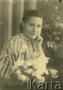 Druga połowa lat 30. do 1941, Kozienice, Polska.
Portret dziewczyny z kwiatami.
Zdjęcie wykonane w atelier fotograficznym żydowskiego fotografa Chaima Bernemana. Przed wojną zakład mieścił się w Kozienicach na rogu ulic Warszawskiej i Maciejowickiej, przed wybuchem wojny albo już w czasie niemieckiej okupacji  został przeniesiony na ulicę Lubelską 13. Cała kolekcja jest datowana na okres od drugiej połowy lat 30-tych do roku 1941, kiedy Chaim Berneman wraz z rodziną został zesłany do obozu pracy w Wolanowie. Berneman zmarł po ucieczce z obozu.
Fot. Chaim Berneman (Chaim Berman), zbiory Ośrodka KARTA
