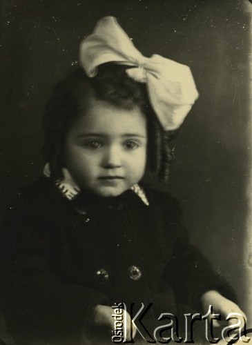 Druga połowa lat 30. do 1941, Kozienice, Polska.
Portret dziewczynki z kokardą we włosach.
Zdjęcie wykonane w atelier fotograficznym żydowskiego fotografa Chaima Bernemana. Przed wojną zakład mieścił się w Kozienicach na rogu ulic Warszawskiej i Maciejowickiej, przed wybuchem wojny albo już w czasie niemieckiej okupacji  został przeniesiony na ulicę Lubelską 13. Cała kolekcja jest datowana na okres od drugiej połowy lat 30-tych do roku 1941, kiedy Chaim Berneman wraz z rodziną został zesłany do obozu pracy w Wolanowie. Berneman zmarł po ucieczce z obozu.
Fot. Chaim Berneman (Chaim Berman), zbiory Ośrodka KARTA