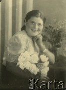 Druga połowa lat 30. do 1941, Kozienice, Polska.
Portret dziewczyny z kwiatami.
Zdjęcie wykonane w atelier fotograficznym żydowskiego fotografa Chaima Bernemana. Przed wojną zakład mieścił się w Kozienicach na rogu ulic Warszawskiej i Maciejowickiej, przed wybuchem wojny albo już w czasie niemieckiej okupacji  został przeniesiony na ulicę Lubelską 13. Cała kolekcja jest datowana na okres od drugiej połowy lat 30-tych do roku 1941, kiedy Chaim Berneman wraz z rodziną został zesłany do obozu pracy w Wolanowie. Berneman zmarł po ucieczce z obozu.
Fot. Chaim Berneman (Chaim Berman), zbiory Ośrodka KARTA