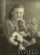 Druga połowa lat 30. do 1941, Kozienice, Polska.
Portret dziewczyny z kwiatami.
Zdjęcie wykonane w atelier fotograficznym żydowskiego fotografa Chaima Bernemana. Przed wojną zakład mieścił się w Kozienicach na rogu ulic Warszawskiej i Maciejowickiej, przed wybuchem wojny albo już w czasie niemieckiej okupacji  został przeniesiony na ulicę Lubelską 13. Cała kolekcja jest datowana na okres od drugiej połowy lat 30-tych do roku 1941, kiedy Chaim Berneman wraz z rodziną został zesłany do obozu pracy w Wolanowie. Berneman zmarł po ucieczce z obozu.
Fot. Chaim Berneman (Chaim Berman), zbiory Ośrodka KARTA