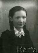 Druga połowa lat 30. do 1941, Kozienice, Polska.
Portret dziewczynki z warkoczami, w szkolnym fartuszku z białym kołnierzykiem.
Zdjęcie wykonane w atelier fotograficznym żydowskiego fotografa Chaima Bernemana. Przed wojną zakład mieścił się w Kozienicach na rogu ulic Warszawskiej i Maciejowickiej, przed wybuchem wojny albo już w czasie niemieckiej okupacji  został przeniesiony na ulicę Lubelską 13. Cała kolekcja jest datowana na okres od drugiej połowy lat 30-tych do roku 1941, kiedy Chaim Berneman wraz z rodziną został zesłany do obozu pracy w Wolanowie. Berneman zmarł po ucieczce z obozu.
Fot. Chaim Berneman (Chaim Berman), zbiory Ośrodka KARTA