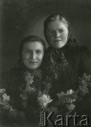 Druga połowa lat 30. do 1941, Kozienice, Polska.
Portret dwóch kobiet w chustkach na głowach, na pierwszym planie girlanda kwiatów.
Zdjęcie wykonane w atelier fotograficznym żydowskiego fotografa Chaima Bernemana. Przed wojną zakład mieścił się w Kozienicach na rogu ulic Warszawskiej i Maciejowickiej, przed wybuchem wojny albo już w czasie niemieckiej okupacji  został przeniesiony na ulicę Lubelską 13. Cała kolekcja jest datowana na okres od drugiej połowy lat 30-tych do roku 1941, kiedy Chaim Berneman wraz z rodziną został zesłany do obozu pracy w Wolanowie. Berneman zmarł po ucieczce z obozu.
Fot. Chaim Berneman (Chaim Berman), zbiory Ośrodka KARTA