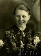 Druga połowa lat 30. do 1941, Kozienice, Polska.
Portret dziewczyny z kwiatami.
Zdjęcie wykonane w atelier fotograficznym żydowskiego fotografa Chaima Bernemana. Przed wojną zakład mieścił się w Kozienicach na rogu ulic Warszawskiej i Maciejowickiej, przed wybuchem wojny albo już w czasie niemieckiej okupacji  został przeniesiony na ulicę Lubelską 13. Cała kolekcja jest datowana na okres od drugiej połowy lat 30-tych do roku 1941, kiedy Chaim Berneman wraz z rodziną został zesłany do obozu pracy w Wolanowie. Berneman zmarł po ucieczce z obozu.
Fot. Chaim Berneman (Chaim Berman), zbiory Ośrodka KARTA