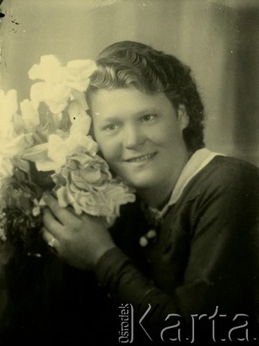 Druga połowa lat 30. do 1941, Kozienice, Polska.
Portret dziewczyny z bukietem kwiatów.
Zdjęcie wykonane w atelier fotograficznym żydowskiego fotografa Chaima Bernemana. Przed wojną zakład mieścił się w Kozienicach na rogu ulic Warszawskiej i Maciejowickiej, przed wybuchem wojny albo już w czasie niemieckiej okupacji  został przeniesiony na ulicę Lubelską 13. Cała kolekcja jest datowana na okres od drugiej połowy lat 30-tych do roku 1941, kiedy Chaim Berneman wraz z rodziną został zesłany do obozu pracy w Wolanowie. Berneman zmarł po ucieczce z obozu.
Fot. Chaim Berneman (Chaim Berman), zbiory Ośrodka KARTA