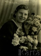 Druga połowa lat 30. do 1941, Kozienice, Polska.
Portret dziewczyny z kwiatami.
Zdjęcie wykonane w atelier fotograficznym żydowskiego fotografa Chaima Bernemana. Przed wojną zakład mieścił się w Kozienicach na rogu ulic Warszawskiej i Maciejowickiej, przed wybuchem wojny albo już w czasie niemieckiej okupacji  został przeniesiony na ulicę Lubelską 13. Cała kolekcja jest datowana na okres od drugiej połowy lat 30-tych do roku 1941, kiedy Chaim Berneman wraz z rodziną został zesłany do obozu pracy w Wolanowie. Berneman zmarł po ucieczce z obozu.
Fot. Chaim Berneman (Chaim Berman), zbiory Ośrodka KARTA