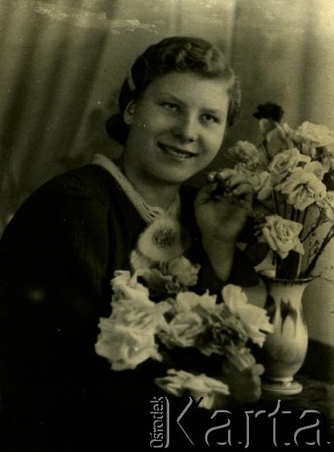 Druga połowa lat 30. do 1941, Kozienice, Polska.
Portret dziewczyny z kwiatami.
Zdjęcie wykonane w atelier fotograficznym żydowskiego fotografa Chaima Bernemana. Przed wojną zakład mieścił się w Kozienicach na rogu ulic Warszawskiej i Maciejowickiej, przed wybuchem wojny albo już w czasie niemieckiej okupacji  został przeniesiony na ulicę Lubelską 13. Cała kolekcja jest datowana na okres od drugiej połowy lat 30-tych do roku 1941, kiedy Chaim Berneman wraz z rodziną został zesłany do obozu pracy w Wolanowie. Berneman zmarł po ucieczce z obozu.
Fot. Chaim Berneman (Chaim Berman), zbiory Ośrodka KARTA
