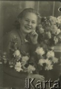 Druga połowa lat 30. do 1941, Kozienice, Polska.
Portret dziewczyny z kwiatami.
Zdjęcie wykonane w atelier fotograficznym żydowskiego fotografa Chaima Bernemana. Przed wojną zakład mieścił się w Kozienicach na rogu ulic Warszawskiej i Maciejowickiej, przed wybuchem wojny albo już w czasie niemieckiej okupacji  został przeniesiony na ulicę Lubelską 13. Cała kolekcja jest datowana na okres od drugiej połowy lat 30-tych do roku 1941, kiedy Chaim Berneman wraz z rodziną został zesłany do obozu pracy w Wolanowie. Berneman zmarł po ucieczce z obozu.
Fot. Chaim Berneman (Chaim Berman), zbiory Ośrodka KARTA