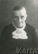 Druga połowa lat 30. do 1941, Kozienice, Polska.
Portret starej kobiety w ciemnym swetrze i moherowym szaliku spiętym broszką.
Zdjęcie wykonane w atelier fotograficznym żydowskiego fotografa Chaima Bernemana. Przed wojną zakład mieścił się w Kozienicach na rogu ulic Warszawskiej i Maciejowickiej, przed wybuchem wojny albo już w czasie niemieckiej okupacji  został przeniesiony na ulicę Lubelską 13. Cała kolekcja jest datowana na okres od drugiej połowy lat 30-tych do roku 1941, kiedy Chaim Berneman wraz z rodziną został zesłany do obozu pracy w Wolanowie. Berneman zmarł po ucieczce z obozu.
Fot. Chaim Berneman (Chaim Berman), zbiory Ośrodka KARTA