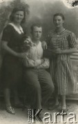Druga połowa lat 30. do 1941, Kozienice, Polska.
Portret dwóch dziewczyn w sukienkach i chłopaka.
Zdjęcie wykonane w atelier fotograficznym żydowskiego fotografa Chaima Bernemana. Przed wojną zakład mieścił się w Kozienicach na rogu ulic Warszawskiej i Maciejowickiej, przed wybuchem wojny albo już w czasie niemieckiej okupacji  został przeniesiony na ulicę Lubelską 13. Cała kolekcja jest datowana na okres od drugiej połowy lat 30-tych do roku 1941, kiedy Chaim Berneman wraz z rodziną został zesłany do obozu pracy w Wolanowie. Berneman zmarł po ucieczce z obozu.
Fot. Chaim Berneman (Chaim Berman), zbiory Ośrodka KARTA