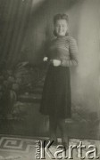 Druga połowa lat 30. do 1941, Kozienice, Polska.
Portret dziewczyny w bluzce w paski i ciemnej spódnicy.
Zdjęcie wykonane w atelier fotograficznym żydowskiego fotografa Chaima Bernemana. Przed wojną zakład mieścił się w Kozienicach na rogu ulic Warszawskiej i Maciejowickiej, przed wybuchem wojny albo już w czasie niemieckiej okupacji  został przeniesiony na ulicę Lubelską 13. Cała kolekcja jest datowana na okres od drugiej połowy lat 30-tych do roku 1941, kiedy Chaim Berneman wraz z rodziną został zesłany do obozu pracy w Wolanowie. Berneman zmarł po ucieczce z obozu.
Fot. Chaim Berneman (Chaim Berman), zbiory Ośrodka KARTA