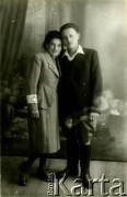 1939-1941, Kozienice, Polska.
Portret dziewczyny z opaską na rękawie żakietu oraz  młodego mężczyzny w marynarce. 
Zdjęcie wykonane w atelier fotograficznym żydowskiego fotografa Chaima Bernemana. Przed wojną zakład mieścił się w Kozienicach na rogu ulic Warszawskiej i Maciejowickiej, przed wybuchem wojny albo już w czasie niemieckiej okupacji  został przeniesiony na ulicę Lubelską 13. Cała kolekcja jest datowana na okres od drugiej połowy lat 30-tych do roku 1941, kiedy Chaim Berneman wraz z rodziną został zesłany do obozu pracy w Wolanowie. Berneman zmarł po ucieczce z obozu.
Fot. Chaim Berneman (Chaim Berman), zbiory Ośrodka KARTA