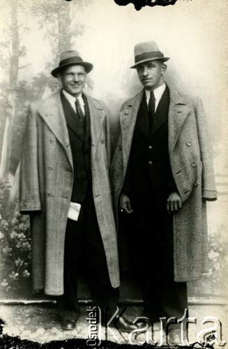 Druga połowa lat 30. do 1941, Kozienice, Polska.
Portret dwóch mężczyzn w garniturach, płaszczach i kapeluszach.
Zdjęcie wykonane w atelier fotograficznym żydowskiego fotografa Chaima Bernemana. Przed wojną zakład mieścił się w Kozienicach na rogu ulic Warszawskiej i Maciejowickiej, przed wybuchem wojny albo już w czasie niemieckiej okupacji został przeniesiony na ulicę Lubelską 13. Cała kolekcja jest datowana na okres od drugiej połowy lat 30-tych do roku 1941, kiedy Chaim Berneman wraz z rodziną został zesłany do obozu pracy w Wolanowie. Berneman zmarł po ucieczce z obozu.
Fot. Chaim Berneman (Chaim Berman), zbiory Ośrodka KARTA