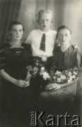 Druga połowa lat 30. do 1941, Kozienice, Polska.
Portret dwóch kobiet z kwiatami oraz chłopca w białej koszuli i krawacie.
Zdjęcie wykonane w atelier fotograficznym żydowskiego fotografa Chaima Bernemana. Przed wojną zakład mieścił się w Kozienicach na rogu ulic Warszawskiej i Maciejowickiej, przed wybuchem wojny albo już w czasie niemieckiej okupacji został przeniesiony na ulicę Lubelską 13. Cała kolekcja jest datowana na okres od drugiej połowy lat 30-tych do roku 1941, kiedy Chaim Berneman wraz z rodziną został zesłany do obozu pracy w Wolanowie. Berneman zmarł po ucieczce z obozu.
Fot. Chaim Berneman (Chaim Berman), zbiory Ośrodka KARTA