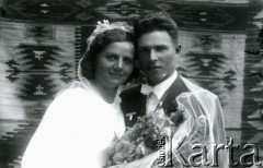 Druga połowa lat 30. do 1941, Kozienice, Polska.
Młoda para z bukietem kwiatów - fotografia ślubna.
Zdjęcie wykonane w atelier fotograficznym żydowskiego fotografa Chaima Bernemana. Przed wojną zakład mieścił się w Kozienicach na rogu ulic Warszawskiej i Maciejowickiej, przed wybuchem wojny albo już w czasie niemieckiej okupacji został przeniesiony na ulicę Lubelską 13. Cała kolekcja jest datowana na okres od drugiej połowy lat 30-tych do roku 1941, kiedy Chaim Berneman wraz z rodziną został zesłany do obozu pracy w Wolanowie. Berneman zmarł po ucieczce z obozu.
Fot. Chaim Berneman (Chaim Berman), zbiory Ośrodka KARTA