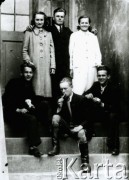 Druga połowa lat 30. do 1941, Kozienice, Polska.
Grupa młodzieży na schodach zakładu fotograficznego przy ul. Lubelskiej 13.
Zdjęcie wykonane w atelier fotograficznym żydowskiego fotografa Chaima Bernemana. Przed wojną zakład mieścił się w Kozienicach na rogu ulic Warszawskiej i Maciejowickiej, przed wybuchem wojny albo już w czasie niemieckiej okupacji został przeniesiony na ulicę Lubelską 13. Cała kolekcja jest datowana na okres od drugiej połowy lat 30-tych do roku 1941, kiedy Chaim Berneman wraz z rodziną został zesłany do obozu pracy w Wolanowie. Berneman zmarł po ucieczce z obozu.
Fot. Chaim Berneman (Chaim Berman), zbiory Ośrodka KARTA