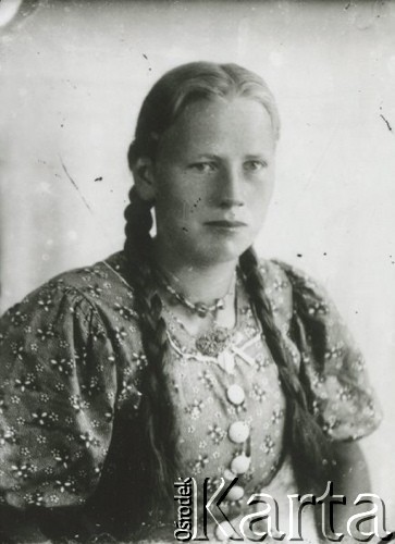 Druga połowa lat 30. do 1941, Kozienice, Polska.
Portret dziewczyny z warkoczami ubranej w sukienkę w kwiaty.
Zdjęcie wykonane w atelier fotograficznym żydowskiego fotografa Chaima Bernemana. Przed wojną zakład mieścił się w Kozienicach na rogu ulic Warszawskiej i Maciejowickiej, przed wybuchem wojny albo już w czasie niemieckiej okupacji został przeniesiony na ulicę Lubelską 13. Cała kolekcja jest datowana na okres od drugiej połowy lat 30-tych do roku 1941, kiedy Chaim Berneman wraz z rodziną został zesłany do obozu pracy w Wolanowie. Berneman zmarł po ucieczce z obozu.
Fot. Chaim Berneman (Chaim Berman), zbiory Ośrodka KARTA
