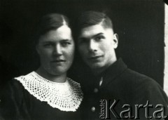 Druga połowa lat 30. do 1941, Kozienice, Polska.
Portret młodej kobiety w bluzce z białym kołnierzykiem oraz mężczyzny w kurtce z odznaką w kształcie sztyletu wpiętą w kołnierz.
Zdjęcie wykonane w atelier fotograficznym żydowskiego fotografa Chaima Bernemana. Przed wojną zakład mieścił się w Kozienicach na rogu ulic Warszawskiej i Maciejowickiej, przed wybuchem wojny albo już w czasie niemieckiej okupacji został przeniesiony na ulicę Lubelską 13. Cała kolekcja jest datowana na okres od drugiej połowy lat 30-tych do roku 1941, kiedy Chaim Berneman wraz z rodziną został zesłany do obozu pracy w Wolanowie. Berneman zmarł po ucieczce z obozu.
Fot. Chaim Berneman (Chaim Berman), zbiory Ośrodka KARTA