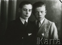 Druga połowa lat 30. do 1941, Kozienice, Polska.
Portret dwóch chłopców w marynarkach, jasnych koszulach i krawatach. Jeden z chłopców ma w klapie marynarki broszkę w kształcie kota, drugi zaś broszkę w kształcie lisa bądź psa.
Zdjęcie wykonane w atelier fotograficznym żydowskiego fotografa Chaima Bernemana. Przed wojną zakład mieścił się w Kozienicach na rogu ulic Warszawskiej i Maciejowickiej, przed wybuchem wojny albo już w czasie niemieckiej okupacji został przeniesiony na ulicę Lubelską 13. Cała kolekcja jest datowana na okres od drugiej połowy lat 30-tych do roku 1941, kiedy Chaim Berneman wraz z rodziną został zesłany do obozu pracy w Wolanowie. Berneman zmarł po ucieczce z obozu.
Fot. Chaim Berneman (Chaim Berman), zbiory Ośrodka KARTA