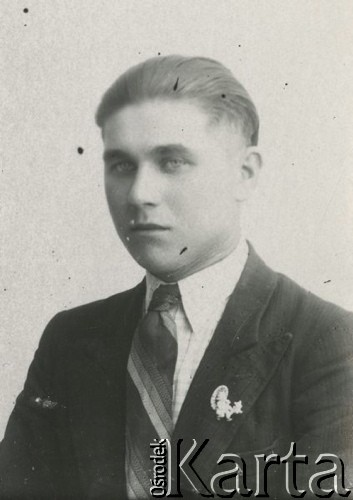 Druga połowa lat 30. do 1941, Kozienice, Polska.
Portret młodego mężczyzny w marynarce, białej koszuli i krawacie. W klapę marynarki jest wpięta broszka w kształcie postaci z parasolką i psa.
Zdjęcie wykonane w atelier fotograficznym żydowskiego fotografa Chaima Bernemana. Przed wojną zakład mieścił się w Kozienicach na rogu ulic Warszawskiej i Maciejowickiej, przed wybuchem wojny albo już w czasie niemieckiej okupacji został przeniesiony na ulicę Lubelską 13. Cała kolekcja jest datowana na okres od drugiej połowy lat 30-tych do roku 1941, kiedy Chaim Berneman wraz z rodziną został zesłany do obozu pracy w Wolanowie. Berneman zmarł po ucieczce z obozu.
Fot. Chaim Berneman (Chaim Berman), zbiory Ośrodka KARTA