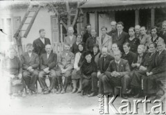 Druga połowa lat 30. do 1941, Kozienice, Polska.
Grupa osób przed drewnianym domem.
Zdjęcie wykonane w atelier fotograficznym żydowskiego fotografa Chaima Bernemana. Przed wojną zakład mieścił się w Kozienicach na rogu ulic Warszawskiej i Maciejowickiej, przed wybuchem wojny albo już w czasie niemieckiej okupacji został przeniesiony na ulicę Lubelską 13. Cała kolekcja jest datowana na okres od drugiej połowy lat 30-tych do roku 1941, kiedy Chaim Berneman wraz z rodziną został zesłany do obozu pracy w Wolanowie. Berneman zmarł po ucieczce z obozu.
Fot. Chaim Berneman (Chaim Berman), zbiory Ośrodka KARTA