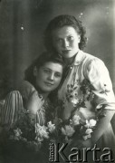 Druga połowa lat 30. do 1941, Kozienice, Polska.
Portret dwóch młodych kobiet z kwiatami.
Zdjęcie wykonane w atelier fotograficznym żydowskiego fotografa Chaima Bernemana. Przed wojną zakład mieścił się w Kozienicach na rogu ulic Warszawskiej i Maciejowickiej, przed wybuchem wojny albo już w czasie niemieckiej okupacji został przeniesiony na ulicę Lubelską 13. Cała kolekcja jest datowana na okres od drugiej połowy lat 30-tych do roku 1941, kiedy Chaim Berneman wraz z rodziną został zesłany do obozu pracy w Wolanowie. Berneman zmarł po ucieczce z obozu.
Fot. Chaim Berneman (Chaim Berman), zbiory Ośrodka KARTA