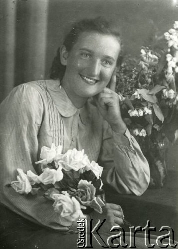 Druga połowa lat 30. do 1941, Kozienice, Polska.
Portret młodej kobiety z kwiatami.
Zdjęcie wykonane w atelier fotograficznym żydowskiego fotografa Chaima Bernemana. Przed wojną zakład mieścił się w Kozienicach na rogu ulic Warszawskiej i Maciejowickiej, przed wybuchem wojny albo już w czasie niemieckiej okupacji został przeniesiony na ulicę Lubelską 13. Cała kolekcja jest datowana na okres od drugiej połowy lat 30-tych do roku 1941, kiedy Chaim Berneman wraz z rodziną został zesłany do obozu pracy w Wolanowie. Berneman zmarł po ucieczce z obozu.
Fot. Chaim Berneman (Chaim Berman), zbiory Ośrodka KARTA