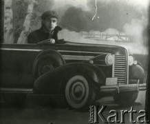 Druga połowa lat 30. do 1941, Kozienice, Polska.
Portret młodego mężczyzny w makiecie samochodu.
Zdjęcie wykonane w atelier fotograficznym żydowskiego fotografa Chaima Bernemana. Przed wojną zakład mieścił się w Kozienicach na rogu ulic Warszawskiej i Maciejowickiej, przed wybuchem wojny albo już w czasie niemieckiej okupacji został przeniesiony na ulicę Lubelską 13. Cała kolekcja jest datowana na okres od drugiej połowy lat 30-tych do roku 1941, kiedy Chaim Berneman wraz z rodziną został zesłany do obozu pracy w Wolanowie. Berneman zmarł po ucieczce z obozu.
Fot. Chaim Berneman (Chaim Berman), zbiory Ośrodka KARTA