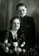 Druga połowa lat 30. do 1941, Kozienice, Polska.
Portret dziewczyny z girlandą kwiatów oraz chłopaka w bluzie z guzikami z polskim orłem.
Zdjęcie wykonane w atelier fotograficznym żydowskiego fotografa Chaima Bernemana. Przed wojną zakład mieścił się w Kozienicach na rogu ulic Warszawskiej i Maciejowickiej, przed wybuchem wojny albo już w czasie niemieckiej okupacji został przeniesiony na ulicę Lubelską 13. Cała kolekcja jest datowana na okres od drugiej połowy lat 30-tych do roku 1941, kiedy Chaim Berneman wraz z rodziną został zesłany do obozu pracy w Wolanowie. Berneman zmarł po ucieczce z obozu.
Fot. Chaim Berneman (Chaim Berman), zbiory Ośrodka KARTA