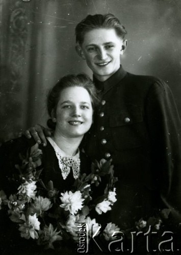 Druga połowa lat 30. do 1941, Kozienice, Polska.
Portret dziewczyny z girlandą kwiatów oraz chłopaka w bluzie z guzikami z polskim orłem.
Zdjęcie wykonane w atelier fotograficznym żydowskiego fotografa Chaima Bernemana. Przed wojną zakład mieścił się w Kozienicach na rogu ulic Warszawskiej i Maciejowickiej, przed wybuchem wojny albo już w czasie niemieckiej okupacji został przeniesiony na ulicę Lubelską 13. Cała kolekcja jest datowana na okres od drugiej połowy lat 30-tych do roku 1941, kiedy Chaim Berneman wraz z rodziną został zesłany do obozu pracy w Wolanowie. Berneman zmarł po ucieczce z obozu.
Fot. Chaim Berneman (Chaim Berman), zbiory Ośrodka KARTA