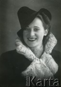 Druga połowa lat 30. do 1941, Kozienice, Polska.
Portret młodej kobiety w płaszczu z futrzanym kołnierzem i w kapeluszu.
Zdjęcie wykonane w atelier fotograficznym żydowskiego fotografa Chaima Bernemana. Przed wojną zakład mieścił się w Kozienicach na rogu ulic Warszawskiej i Maciejowickiej, przed wybuchem wojny albo już w czasie niemieckiej okupacji został przeniesiony na ulicę Lubelską 13. Cała kolekcja jest datowana na okres od drugiej połowy lat 30-tych do roku 1941, kiedy Chaim Berneman wraz z rodziną został zesłany do obozu pracy w Wolanowie. Berneman zmarł po ucieczce z obozu.
Fot. Chaim Berneman (Chaim Berman), zbiory Ośrodka KARTA