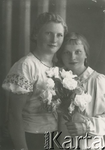 Druga połowa lat 30. do 1941, Kozienice, Polska.
Portret kobiety i dziewczynki z kwiatami.
Zdjęcie wykonane w atelier fotograficznym żydowskiego fotografa Chaima Bernemana. Przed wojną zakład mieścił się w Kozienicach na rogu ulic Warszawskiej i Maciejowickiej, przed wybuchem wojny albo już w czasie niemieckiej okupacji został przeniesiony na ulicę Lubelską 13. Cała kolekcja jest datowana na okres od drugiej połowy lat 30-tych do roku 1941, kiedy Chaim Berneman wraz z rodziną został zesłany do obozu pracy w Wolanowie. Berneman zmarł po ucieczce z obozu.
Fot. Chaim Berneman (Chaim Berman), zbiory Ośrodka KARTA