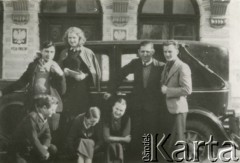 Druga połowa lat 30. do 1939, Kozienice, Polska.
Grupa maturzystów obok samochodu, w tle budynek Wydziału Powiatowego.
Zdjęcie wykonane w atelier fotograficznym żydowskiego fotografa Chaima Bernemana. Przed wojną zakład mieścił się w Kozienicach na rogu ulic Warszawskiej i Maciejowickiej, tuż przed wybuchem wojny albo już w czasie niemieckiej okupacji  został przeniesiony na ulicę Lubelską 13. Cała kolekcja jest datowana na okres od drugiej połowy lat 30-tych do roku 1941, kiedy Chaim Berneman wraz z rodziną został zesłany do obozu pracy w Wolanowie. Berneman zmarł na tyfus po ucieczce z obozu.
Fot. Chaim Berneman (Chaim Berman), zbiory Ośrodka KARTA