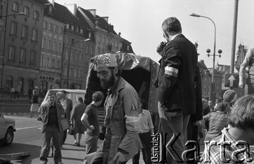Po 13.05.1981, Warszawa, Polska.
Przygotowania przed Kościołem św. Anny do mszy zorganizowanej po zamachu na Jana Pawła II - służby porządkowe zgromadzone na Krakowskim Przedmieściu. Na pierwszym planie - mężczyzna w czapce, na której widnieje godło papieskie.
Fot. NN, zbiory Ośrodka KARTA/Independent Polish Agency (IPA) przekazał Józef Lebenbaum