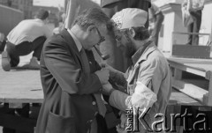 Po 13.05.1981, Warszawa, Polska.
Przygotowania przed Kościołem św. Anny do mszy zorganizowanej po zamachu na Jana Pawła II - mężczyzna z fajką oraz mężczyzna w czapce, na której widnieje godło papieskie.  
Fot. NN, zbiory Ośrodka KARTA/Independent Polish Agency (IPA) przekazał Józef Lebenbaum