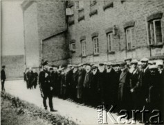 1939-1942, Płońsk, Polska.
Żydzi na dziedzińcu więziennym, pilnowani przez funkcjonariusza Einsatzkommando 3. Fotografię wykonał funkcjonariusz Einsatzkommando 3, wchodzący w skład Einsatzgruppe V, dowodzoną przez Ernsta Damzoga.  
Fot. NN, zbiory Ośrodka KARTA, przekazał Jan Ptasiński